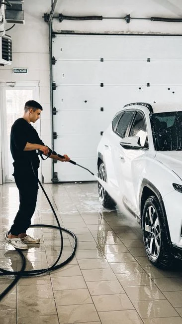 Une personne remplace un sac dans un aspirateur jaune posé sur un tapis à motifs.